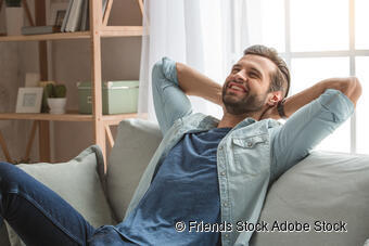 Ein glücklicher Mann entspannt sich auf einer Couch