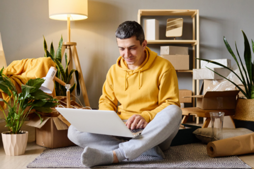 Ein Mann in einem Wohnzimmer. Auf seinem Schoß befindet sich ein Laptop. Ein Mann in einem Wohnzimmer. Auf seinem Schoß befindet sich ein Laptop.