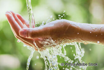 Ein Wasserstrahl fällt einer Frau auf die Handfläche Ein Wasserstrahl fällt einer Frau auf die Handfläche
